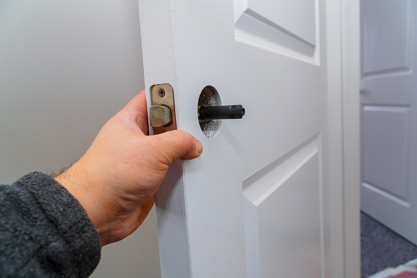 Hands repairing a door lock with a door knobs